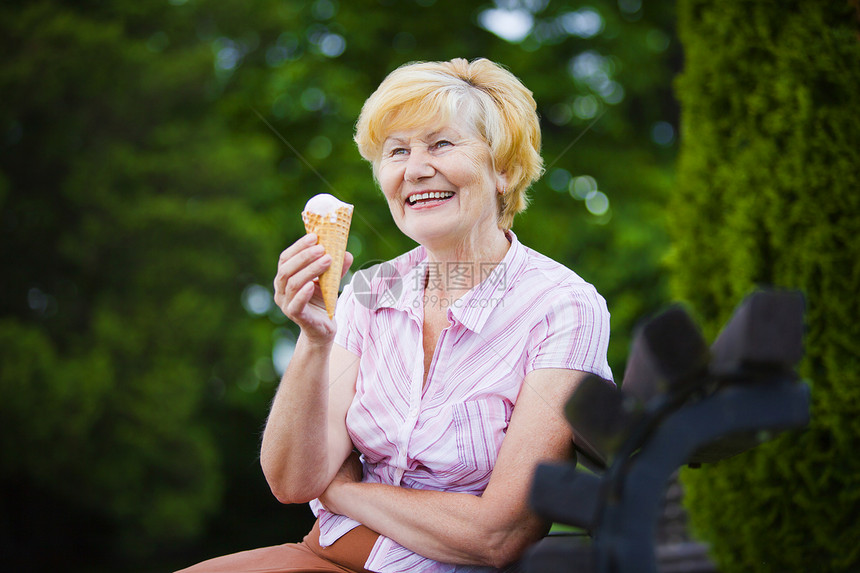 白发女人公园的长凳上用冰淇淋放松图片