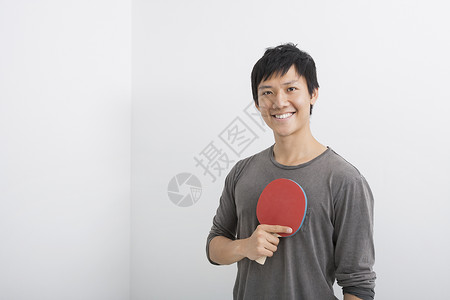 快乐的中男子手持乒乓球桨的肖像图片