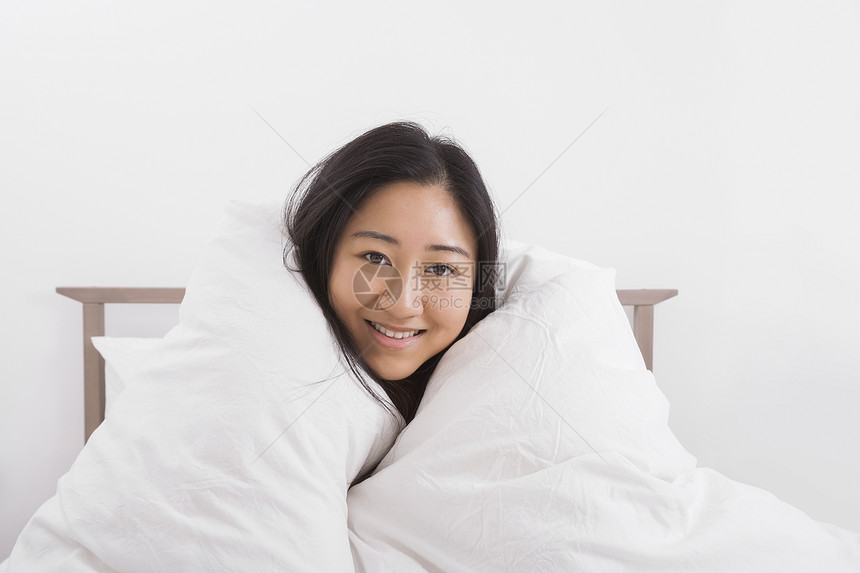 床上裹着被子的快乐女人的肖像图片
