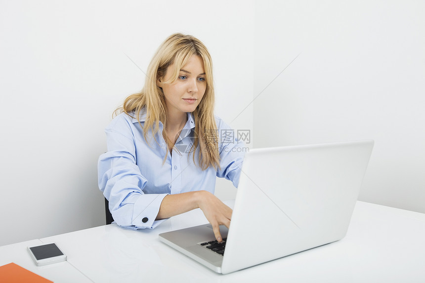 轻的女商人办公室的桌子上用笔记本电脑图片