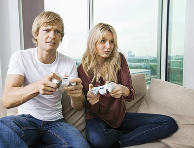 放松的轻夫妇家里的客厅里玩电子游戏图片