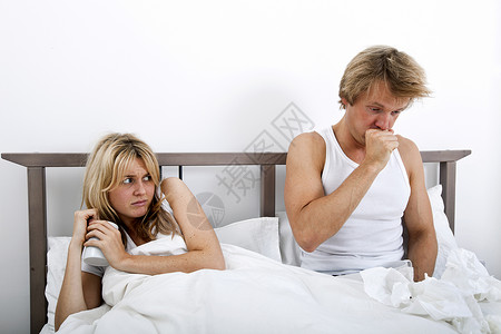 害怕的女人看着男人床上咳嗽图片