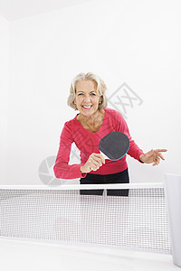 快乐的高级女子打乒乓球的肖像图片