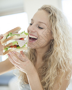 耐烦快乐的女人家里吃大三明治背景