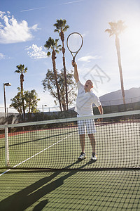 资深男网球运动员球场上打球图片