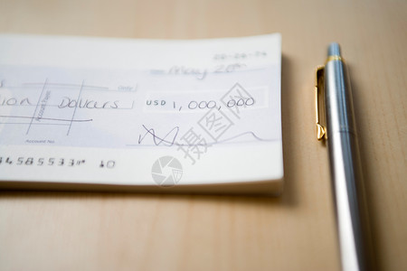 钢笔笔迹100万美元的支票躺桌子特写的钢笔旁边背景