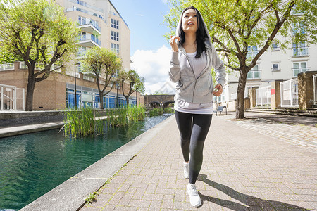 整整段适合的轻女人运河上靠建筑物奔跑图片