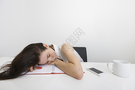 疲惫的女商人睡办公室的桌子上图片