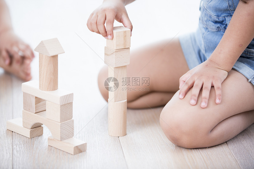 硬木地板上玩积木的女孩的中段图片