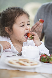 可爱的小女孩早餐桌上爸爸吃草莓图片