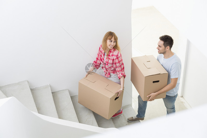 幸福的夫妇新房子里把移动的箱子搬楼梯上图片
