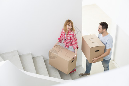 幸福的夫妇新房子里把移动的箱子搬楼梯上图片