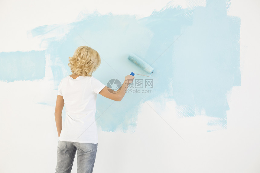 女子画墙的后视镜与油漆滚筒图片