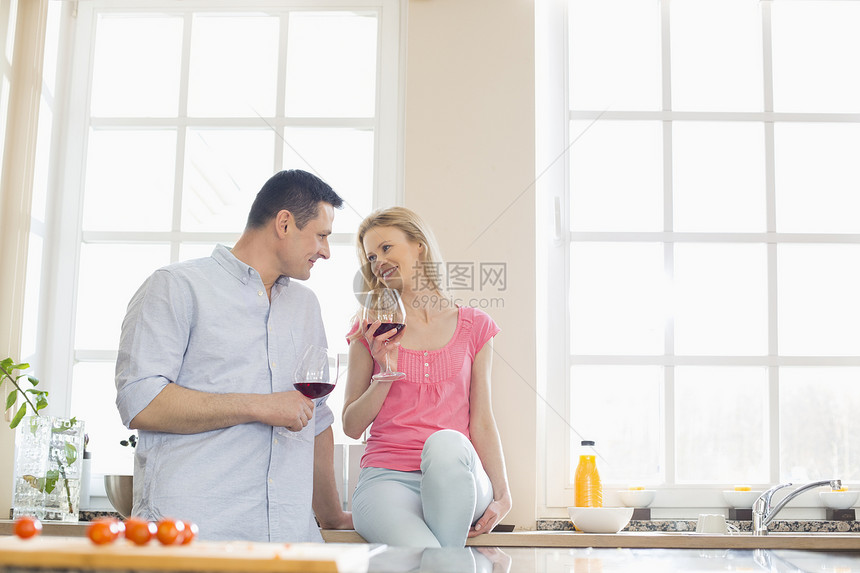 幸福的夫妇厨房喝红酒时互相看着图片