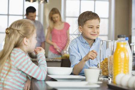 吃饱饭男孩兄弟姐妹餐桌上吃早餐,父母后台饭背景