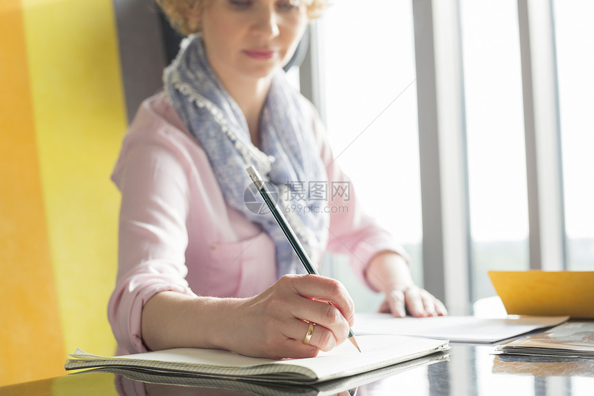 中女商人办公室办公桌上的记事本上写字图片