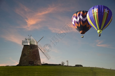 可爱的形象热气球旧风车上日落山顶与充满活力的天空图片