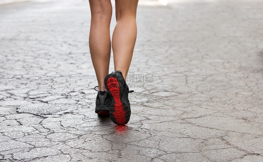 后镜头的轻女士带着健身鞋,条破碎的时尚道路上行走图片