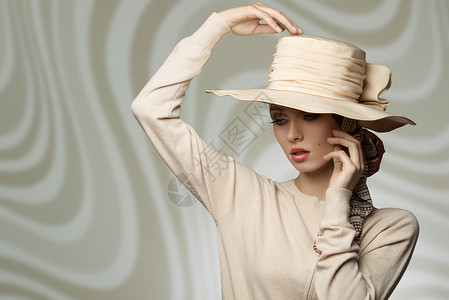 可爱优雅的时尚女孩戴着协调的米色帽子连衣裙,时尚的姿势与浪漫的表情图片