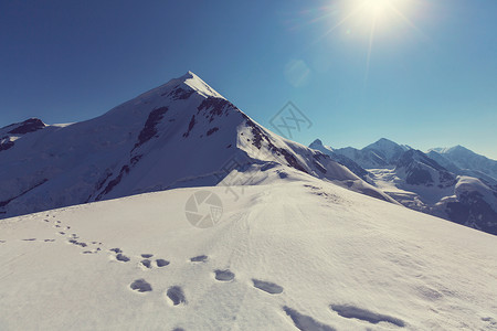 在雪山被太阳光照射着的脚印高清图片