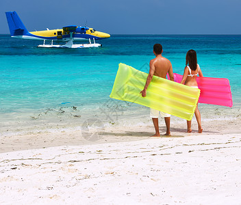 夫妇带着充气筏,看着马尔代夫热带海滩上达的水上飞机没品牌名称版权象图片