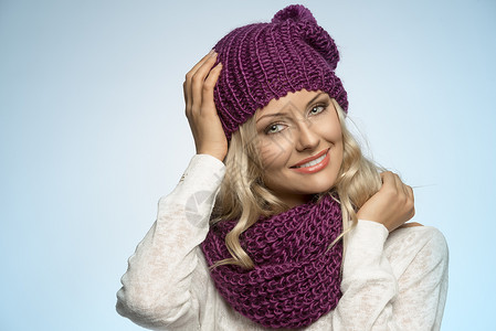 轻感的金发女孩戴着紫色围巾帽子,穿着浅蓝色背景的冬装图片