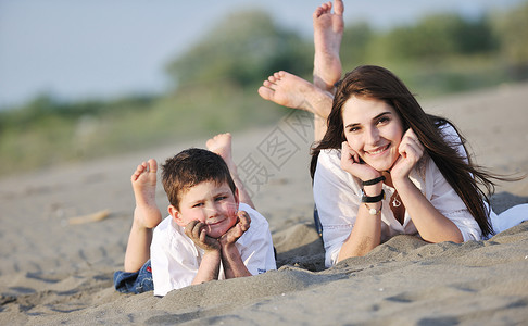 游泳沙滩男孩快乐的轻母亲儿子放松玩沙滩游戏夏天的季节背景