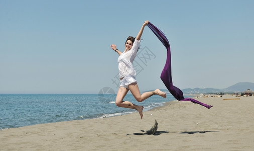 美丽的轻女人海滩上戴着围巾,放松微笑,玩得开心图片