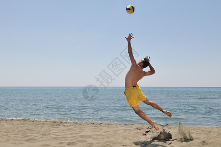 男子打排球男子沙滩排球比赛运动员跳热沙上背景