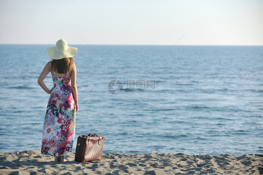 海滩上着手提箱旅行袋的女人代表着异国情调奢华的逃避自由图片