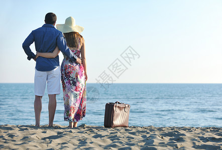 风趣夫妇海滩上带着旅行袋,代表自由趣的蜜月背景