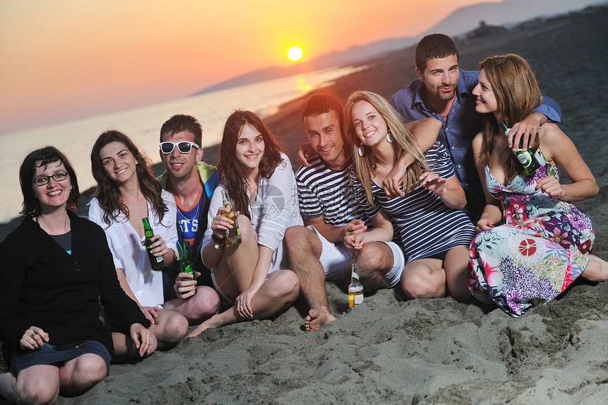 群轻人美丽的日落海滩上享受夏天的聚会图片