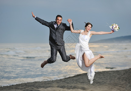 快乐,刚刚结婚的轻夫妇庆祝,并美丽的海滩日落玩得开心图片