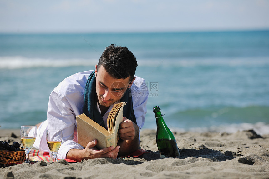 轻人美丽的晴天海滩上放松,同时阅读代表暑期学校教育理念的书籍图片