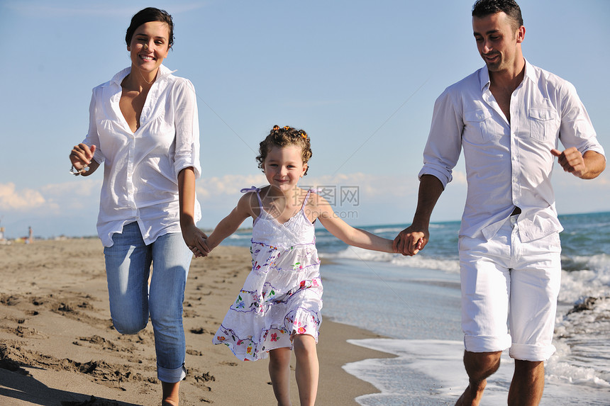 穿着白色衣服的幸福的轻家庭美丽的海滩度假时玩得很开心图片