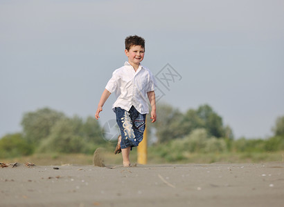 可爱的小男孩海滩上跑步,玩得开心图片