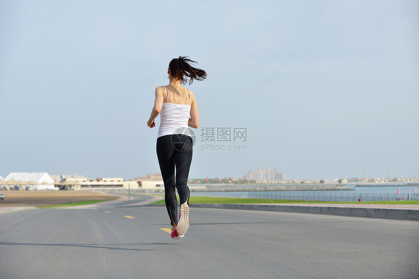 城市公园跑步早上外慢跑的女子跑步者,背景迪拜城市的场景图片