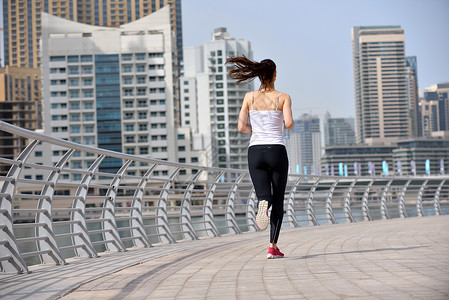 城市公园跑步早上外慢跑的女子跑步者,背景迪拜城市的场景图片