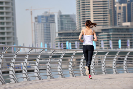 城市公园跑步早上外慢跑的女子跑步者,背景迪拜城市的场景图片