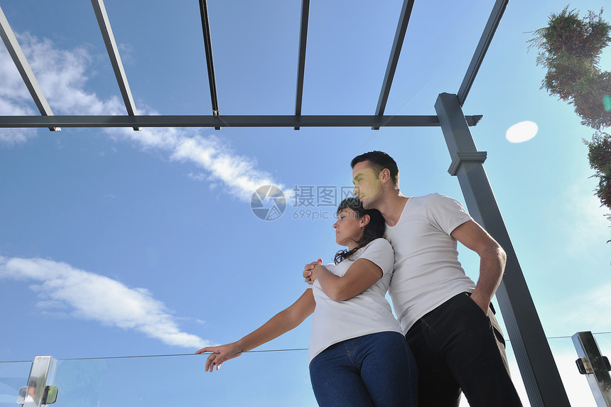 快乐的轻夫妇户外阳台上放松,背景海洋蓝天图片