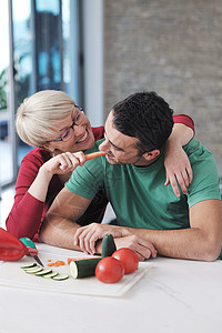 快乐的轻夫妇现代厨房室内玩得开心,同时准备新鲜水果蔬菜食品沙拉图片