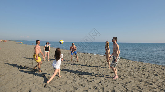 打排球的孩子轻人体玩得开心,阳光明媚的夏日打沙滩排球背景