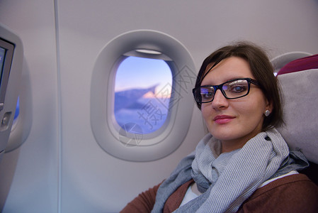 打开窗口快乐的轻旅游妇女坐飞机上看着温多夫,度假背景