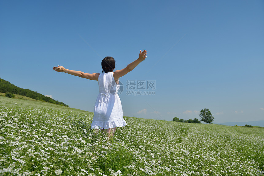 轻快乐的女人绿色的田野,蓝天的背景图片