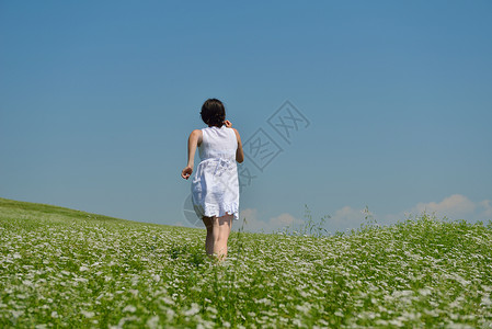 绿色连衣裙轻快乐的女人绿色的田野,蓝天的背景背景