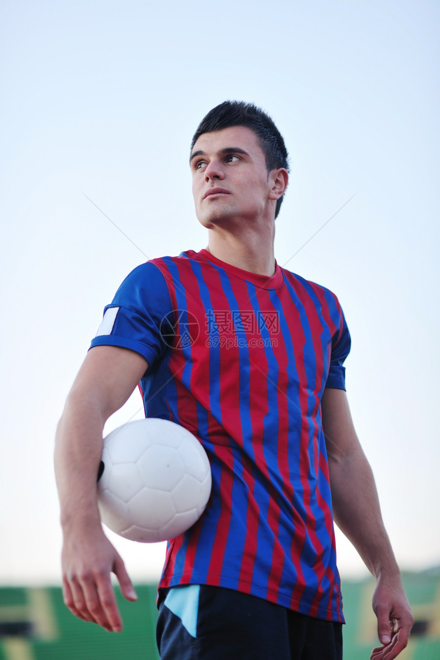 足球体育场绿草的轻英俊足球运动员的肖像图片