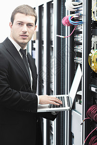 轻的IT工程师商务人员与薄的现代铝笔记本电脑网络服务器机房图片