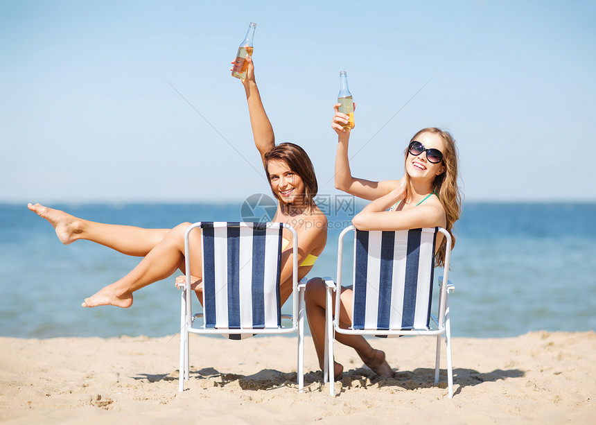 暑假假期女孩海滩椅子上晒太阳喝酒图片