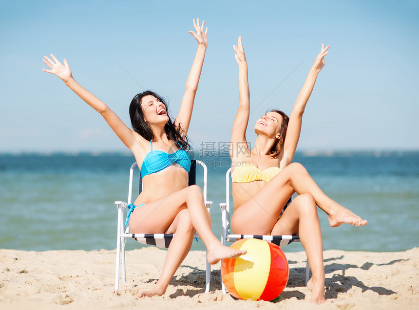 暑假假期女孩们海滩椅子上晒太阳图片