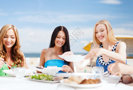 暑假假期女孩们海滩上的咖啡馆里吃喝图片